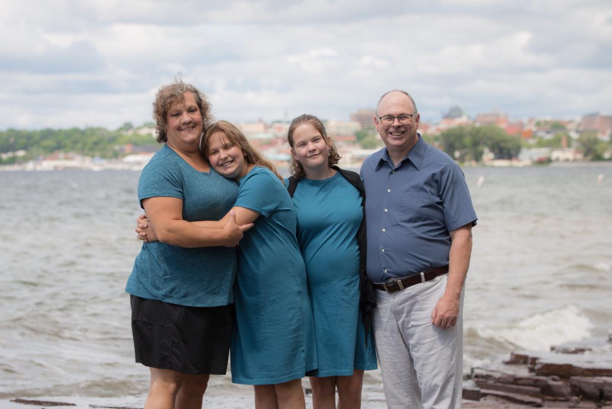 Parents on both sides hugging their young adult children by the lake