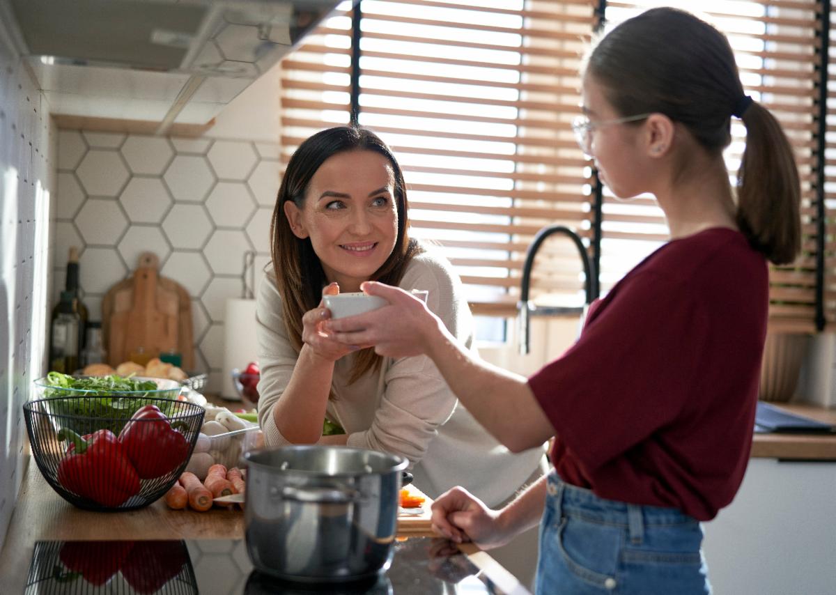 A parent and youth cook together and share a bowl of food
