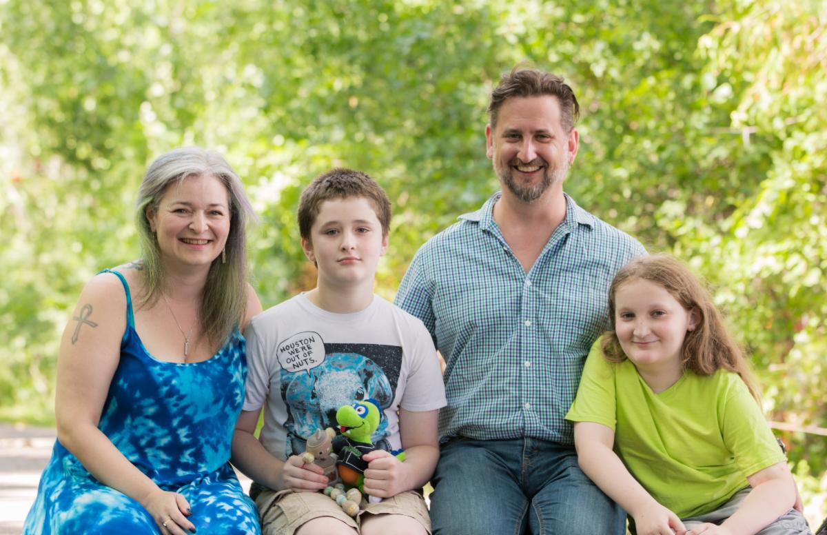 Family sitting on the lawn with trees overhead