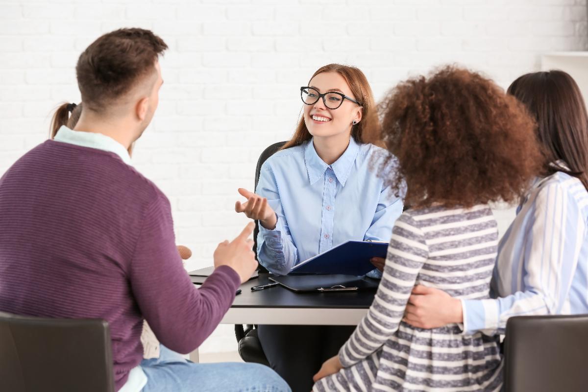 A team meeting with parents, youth and a facilitator sitting around a table