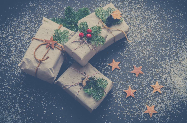 three packages wrapped in brown paper with green pine needles as decoration and brown twine
