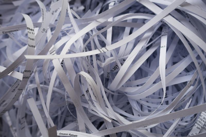 Image of thin strips of shredded white paper with some printing on them.