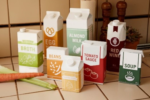 Cartons labeled broth, egg nog, almond milk, beans, soup, tomato sauce sitting on a counter top