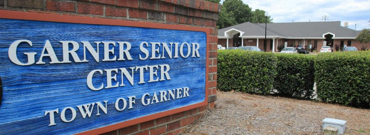 Exterior image of the blue Garner Senior Sign in front of the building.