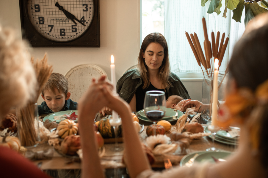 Family is praying together before enjoying a Thanksgiving meal.