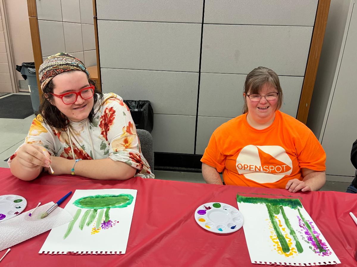 Two women are painting with watercolors in a Disability Network Eastern Michigan arts and crafts class.