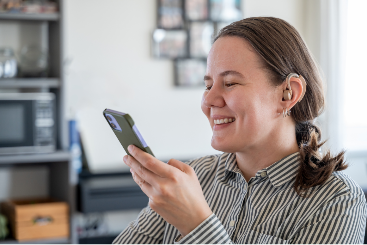 Woman with a hearing aid using a smart phone.