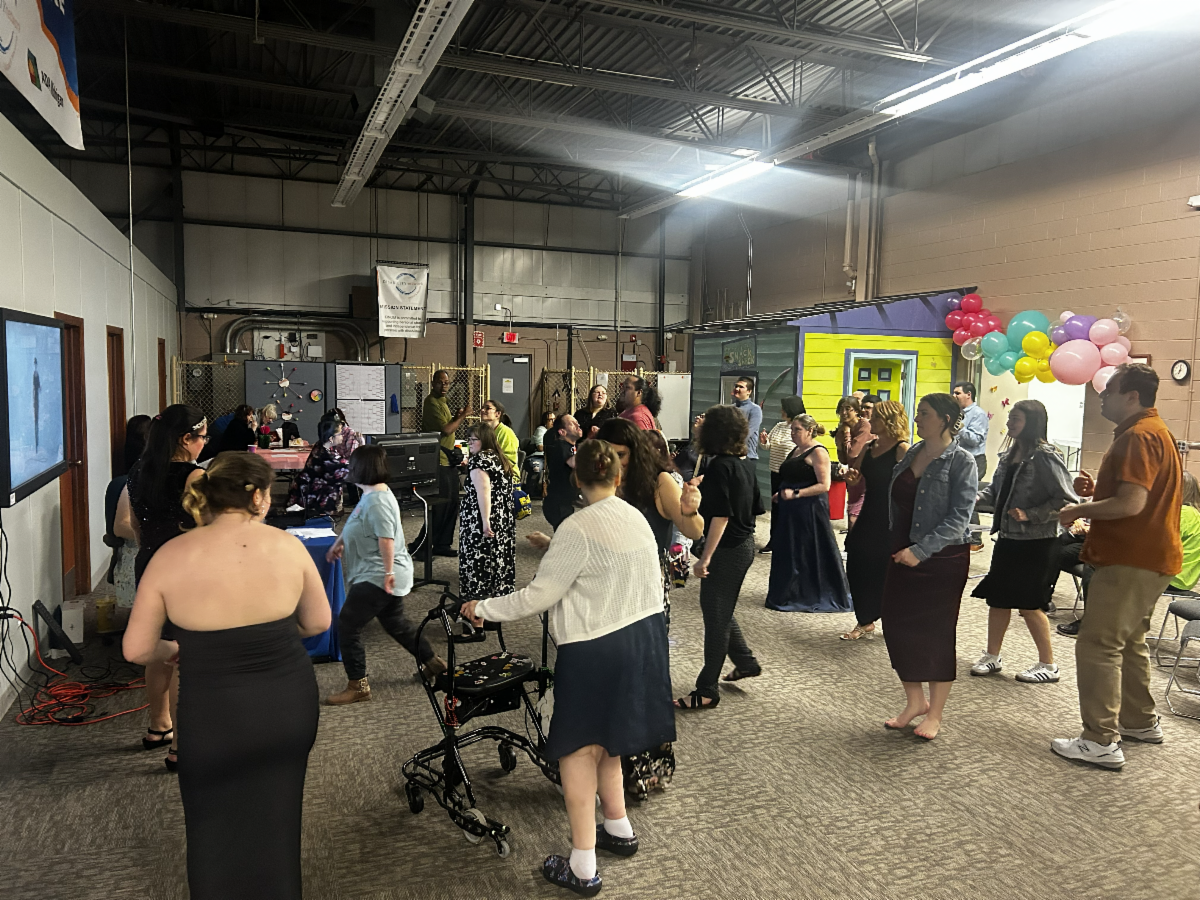 A diverse group of people dancing at a Disability Network Eastern Michigan karaoke dance party.
