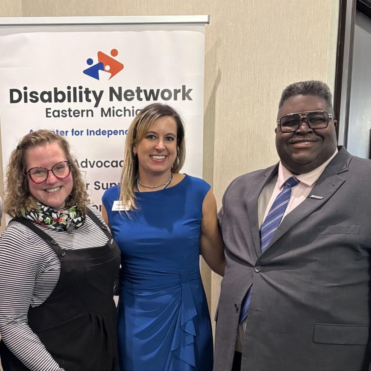 Two staff from Matrix Health and Fitness, an Art from the Heart 2025 sponsor, pose for a photo at the event with Disability Network Eastern Michigan staff, Lauren Baker.