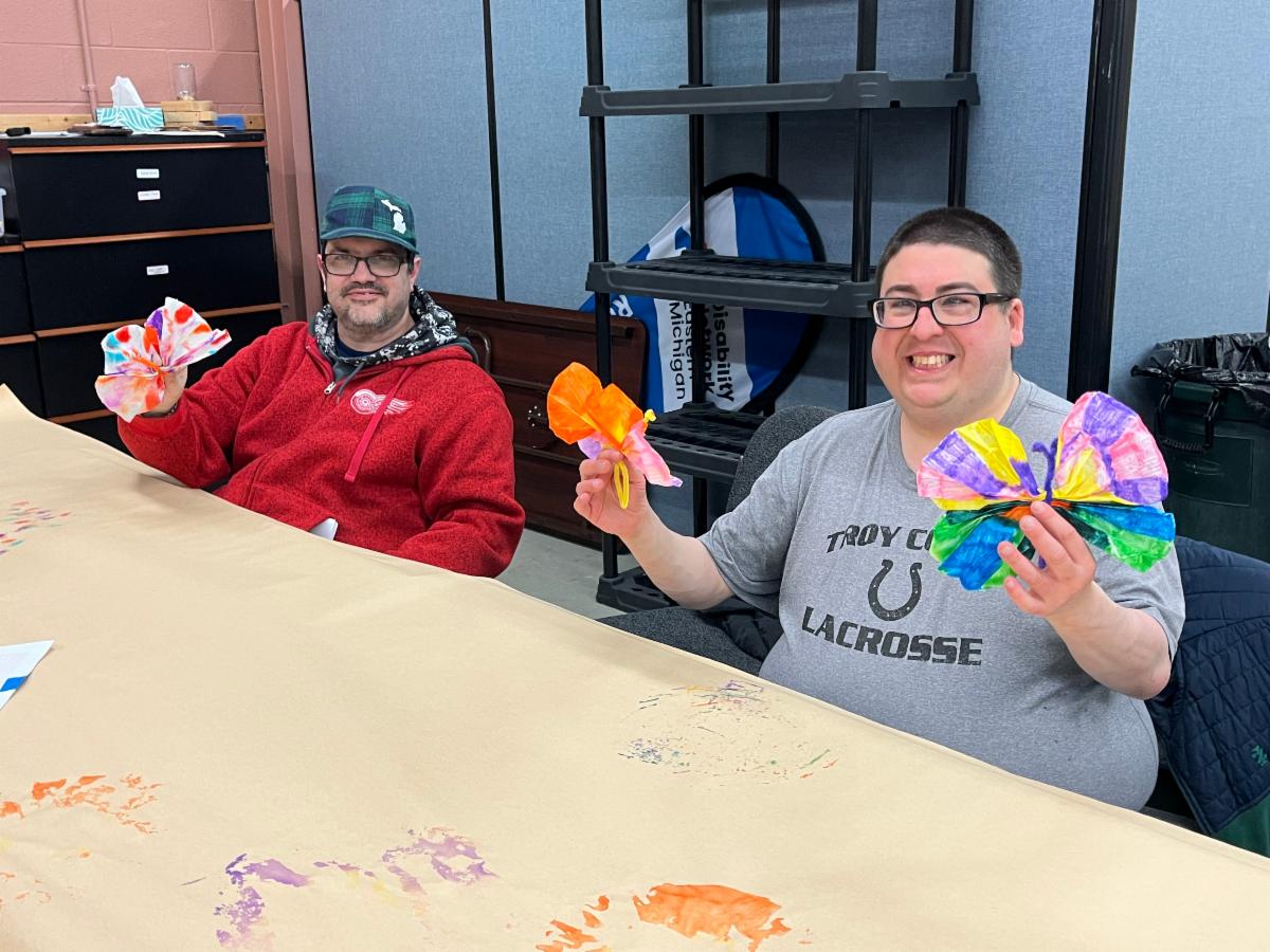 Craft class participants hold up the paper butterflies they made.