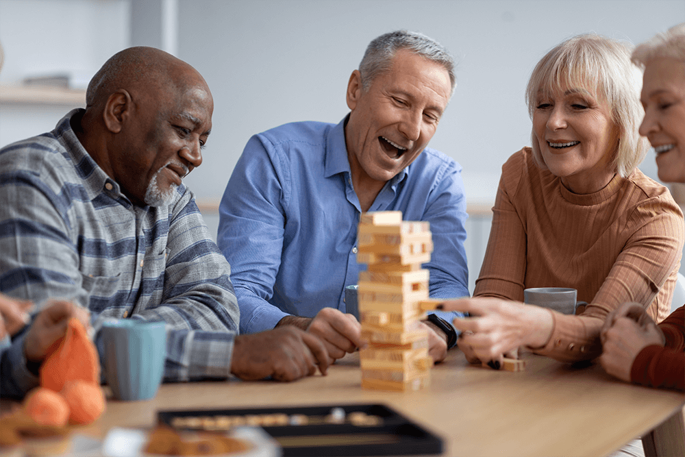 A group of adults are seated around a table playing Jenga.