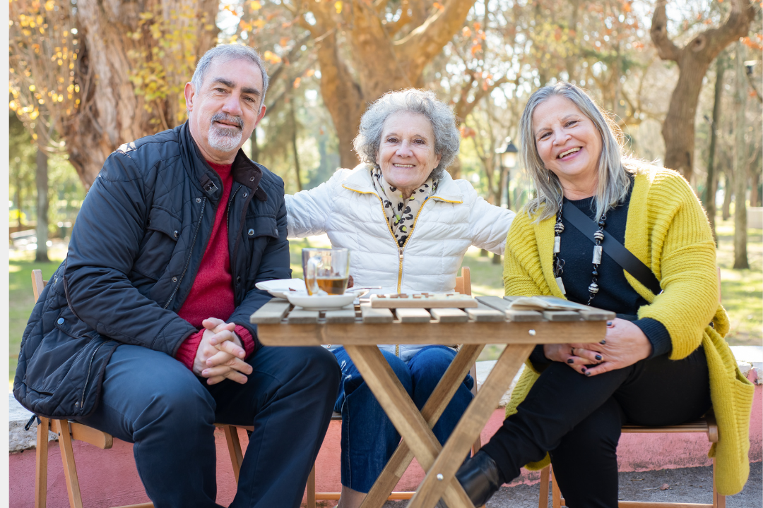 Three older adults pose for a photo outdoors.