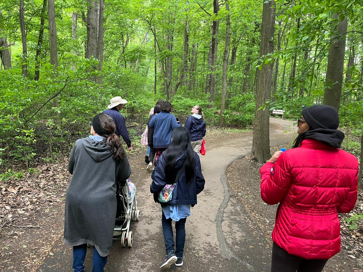 A group of people are taking a guided nature walk on a paved park path.