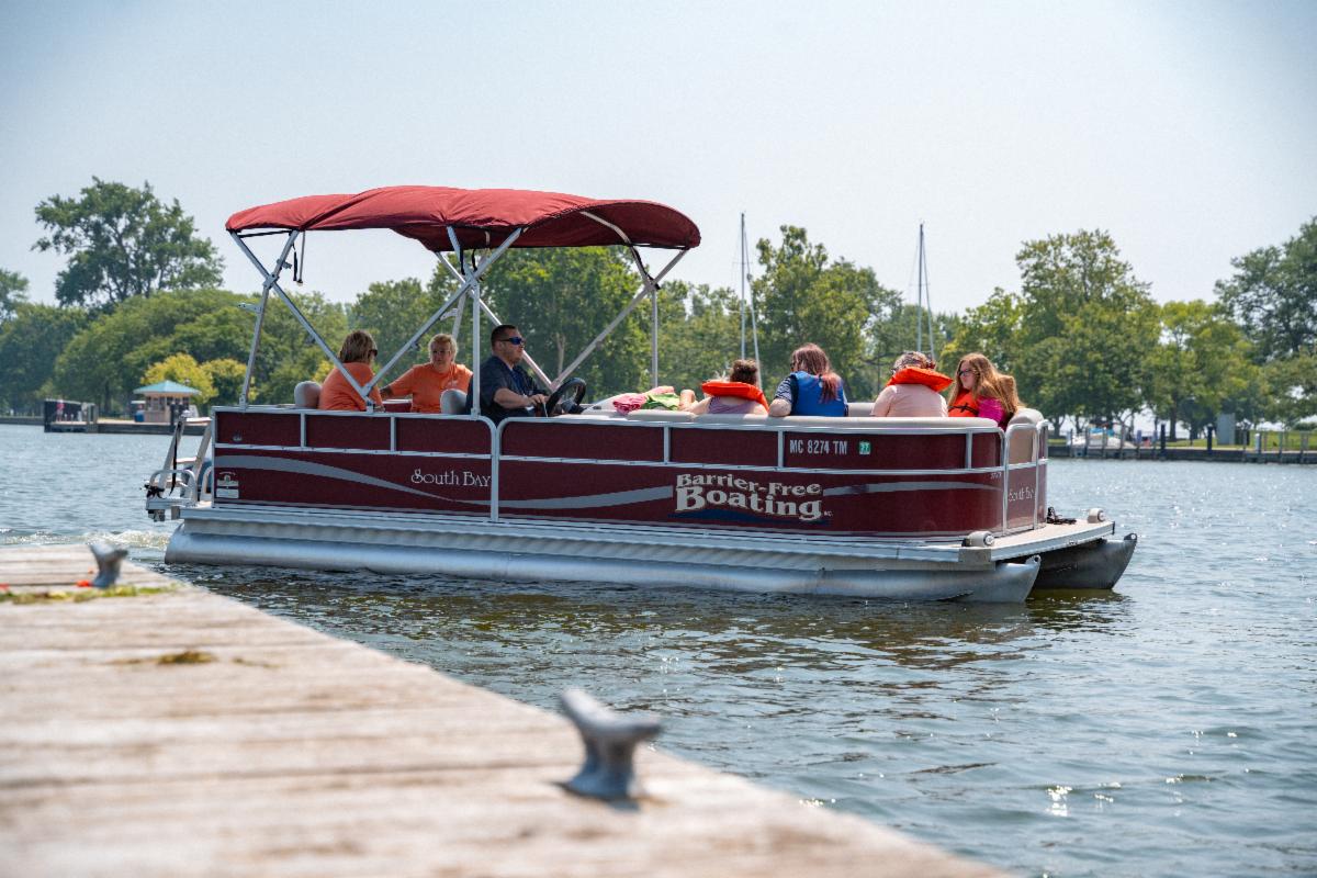 People wearing life jackets are taking a pontoon ride at DiversAbility Day.