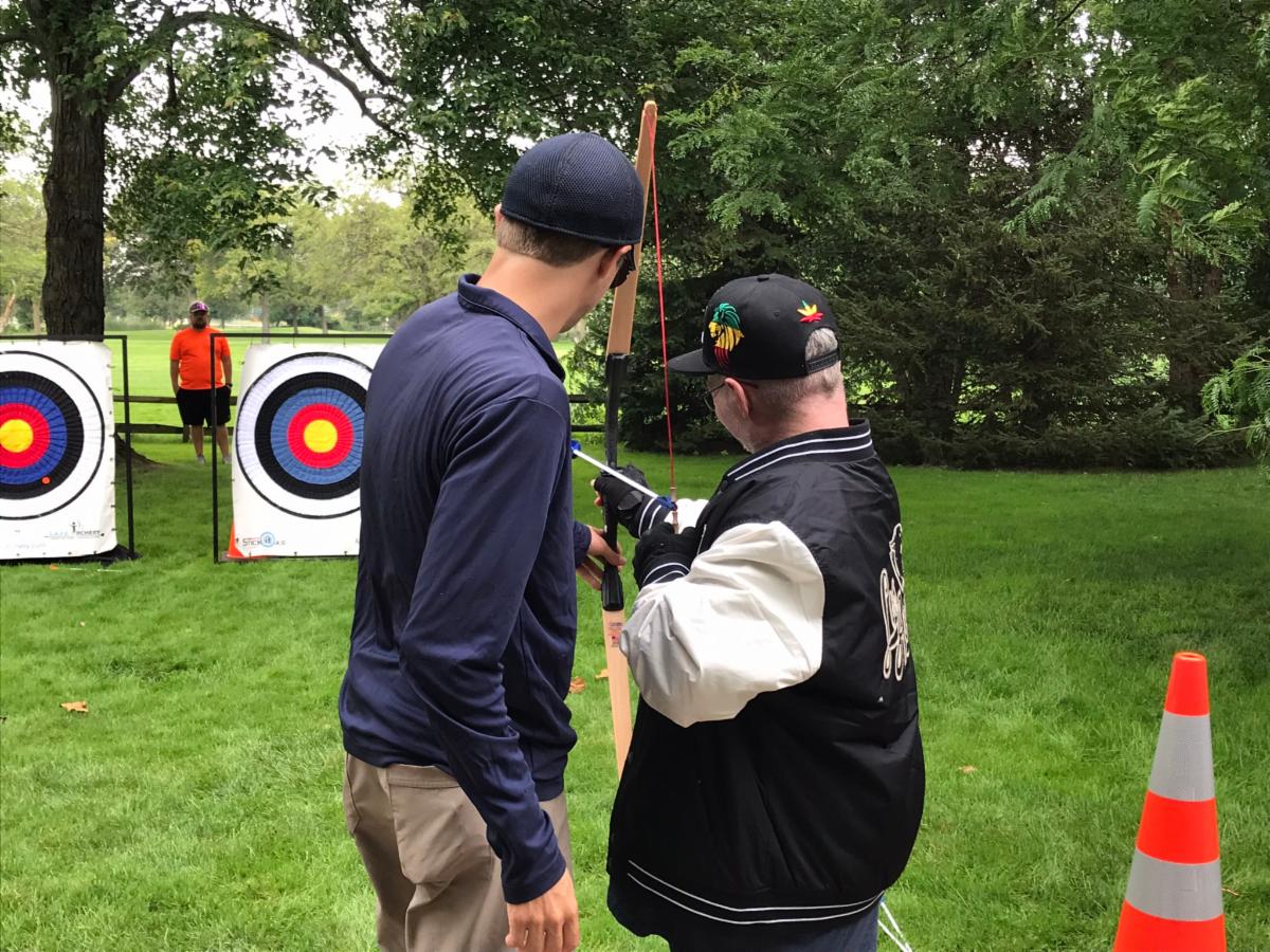 A man receives an adaptive archery lesson.