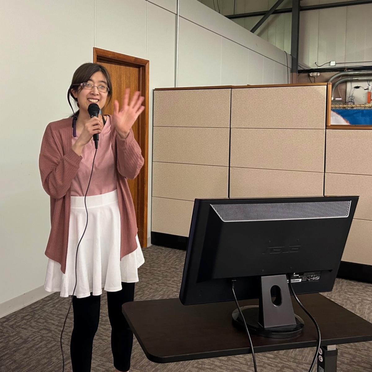 A young woman waves as she sings karaoke. 