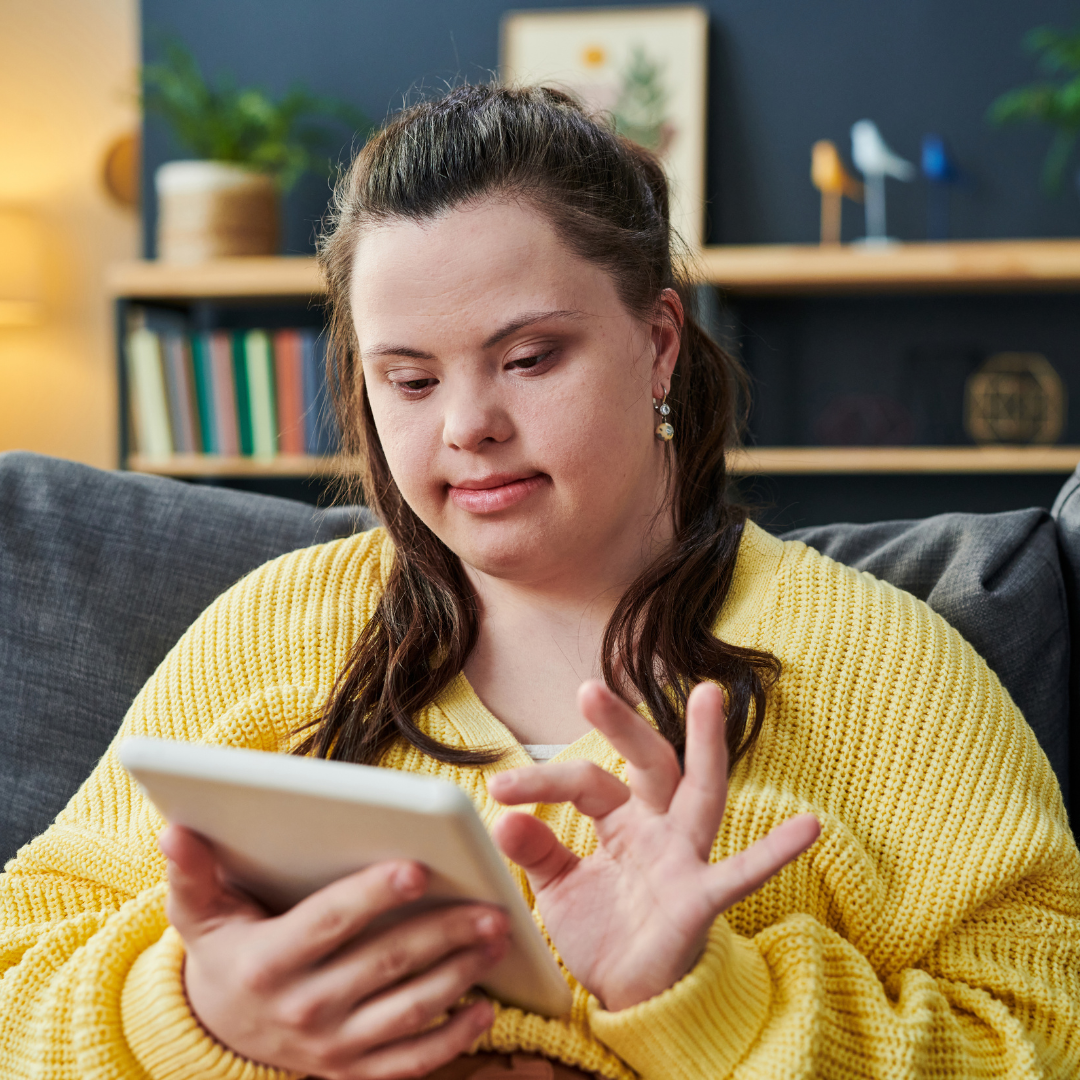 A young woman with Down Syndrome is playing a virtual game on a tablet.