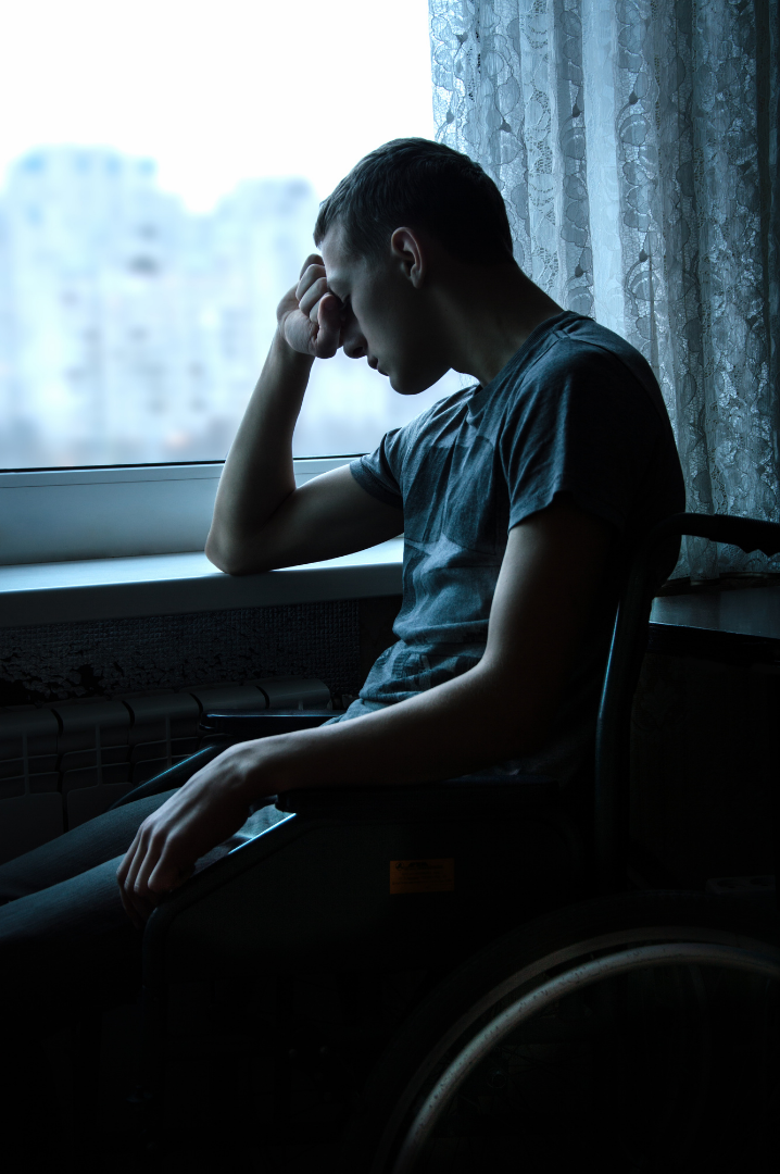 A wheelchair user holds his head in despair.