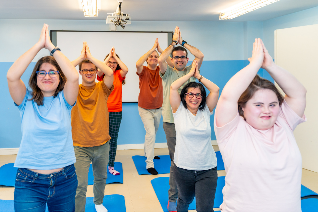 A group of people with disabilities in a class doing yoga poses.