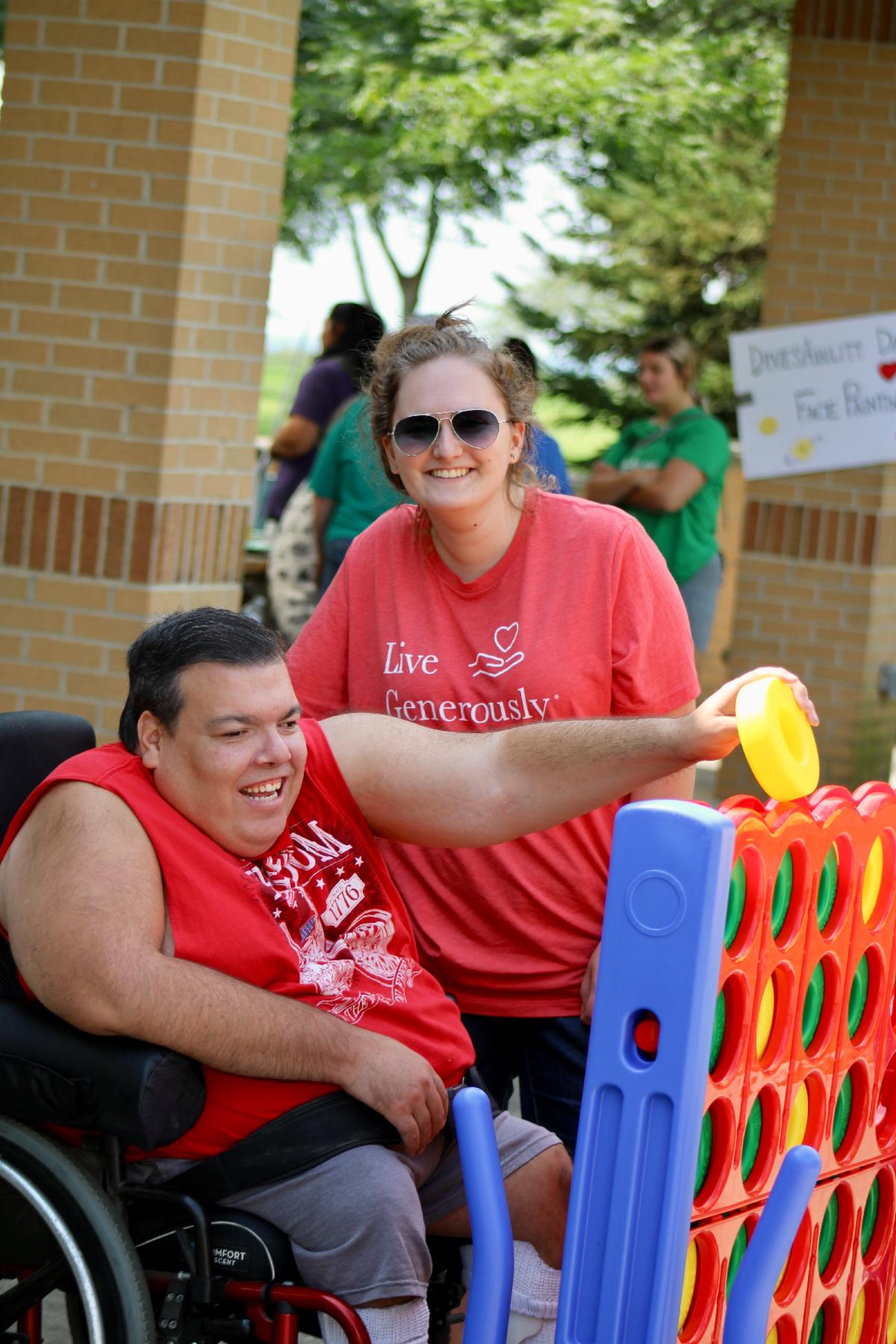 Two people playing 4 in a Row Connect Game. One person uses a wheelchair.