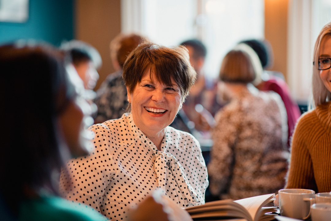 Woman laughing and smiling, enjoying the company of her book club members.