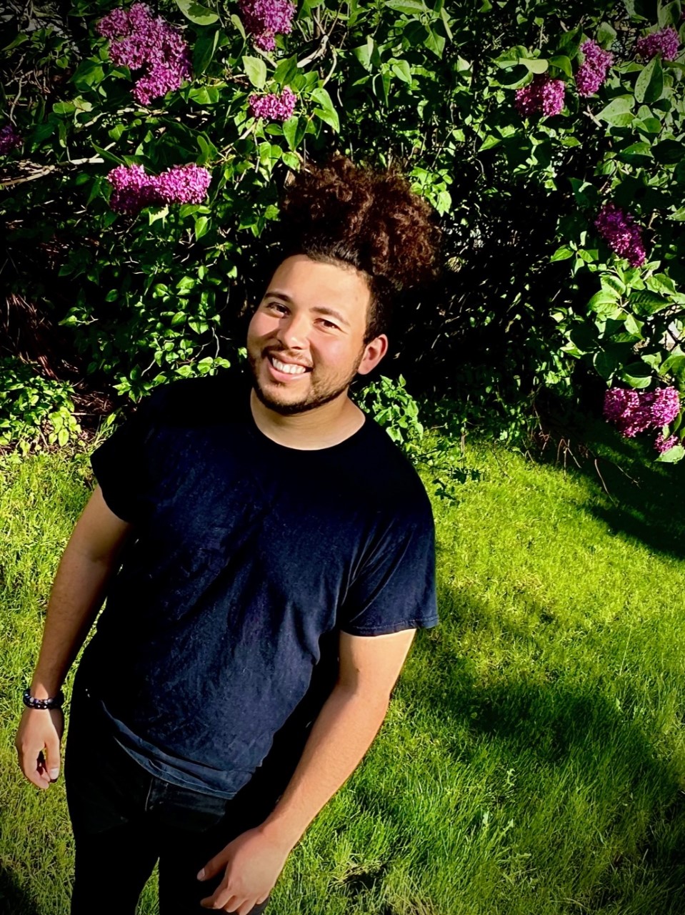 Oscar Arce outside in front of flower bushes