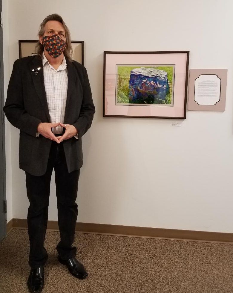 Photographer John Kellen stands in front of one of his photographs in the gallery.