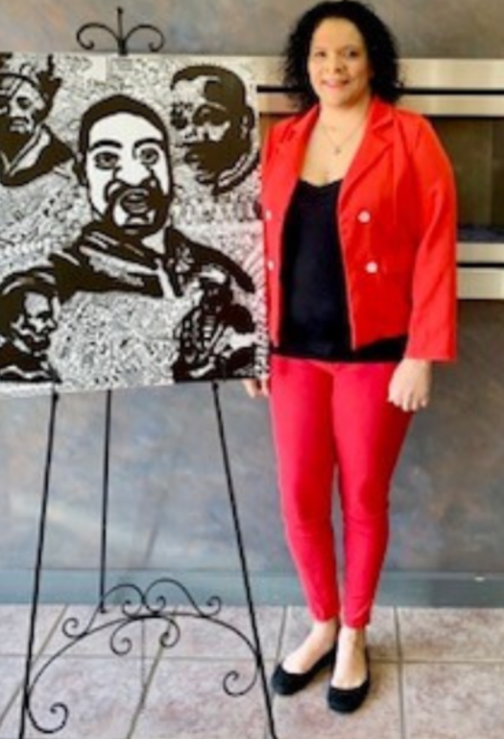 Artist Jammie Niemeyer standing next to a black and white painting of hers.