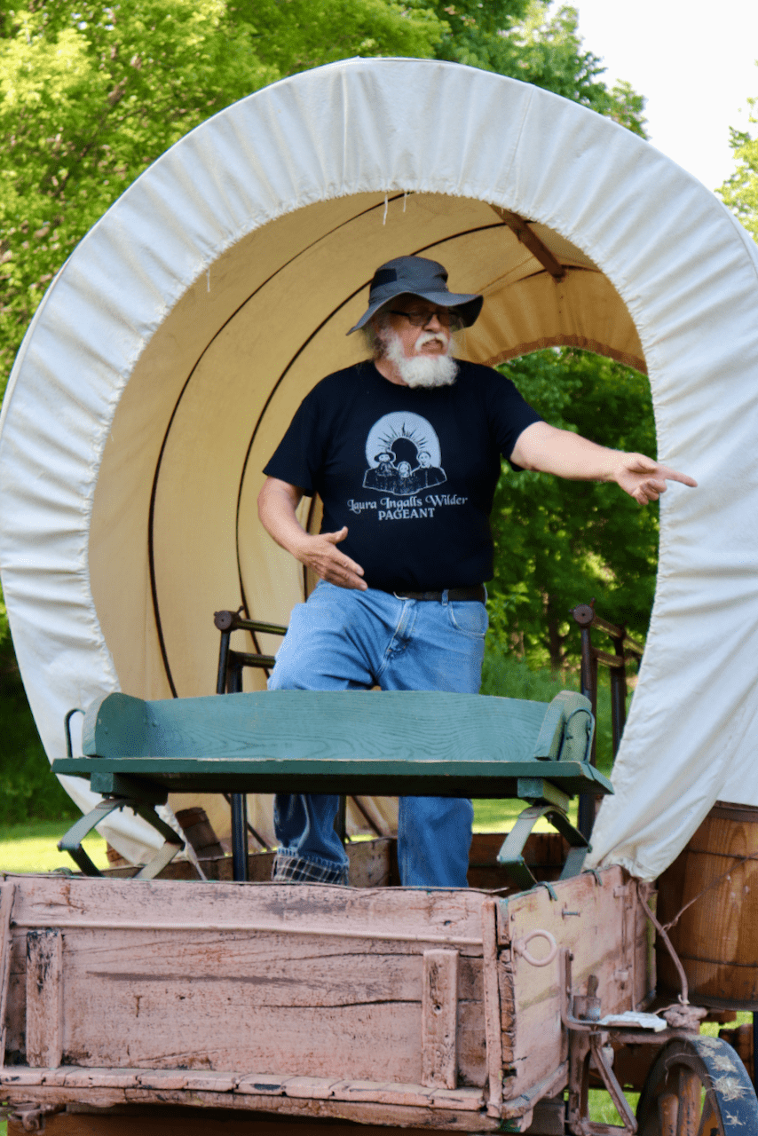 Bill Richards giving directions while standing in a covered wagon 