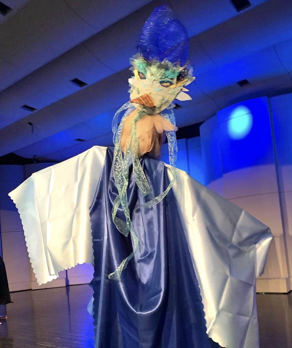 Costumed stage actor, costume has large elaborate mask with beak and many feathers