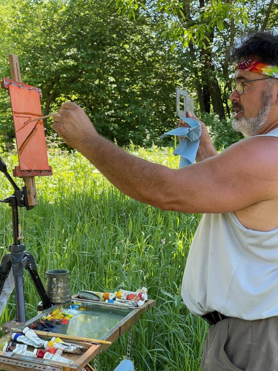 Instructor John Sterner paints outside.