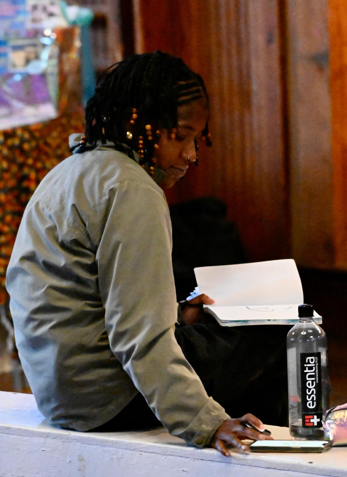 Tisha works on a sketchbook while on a bench