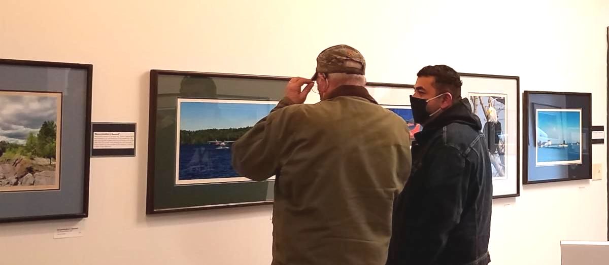 Two visitors in face masks look at John Kellen's framed photographs in the SMAC Gallery.