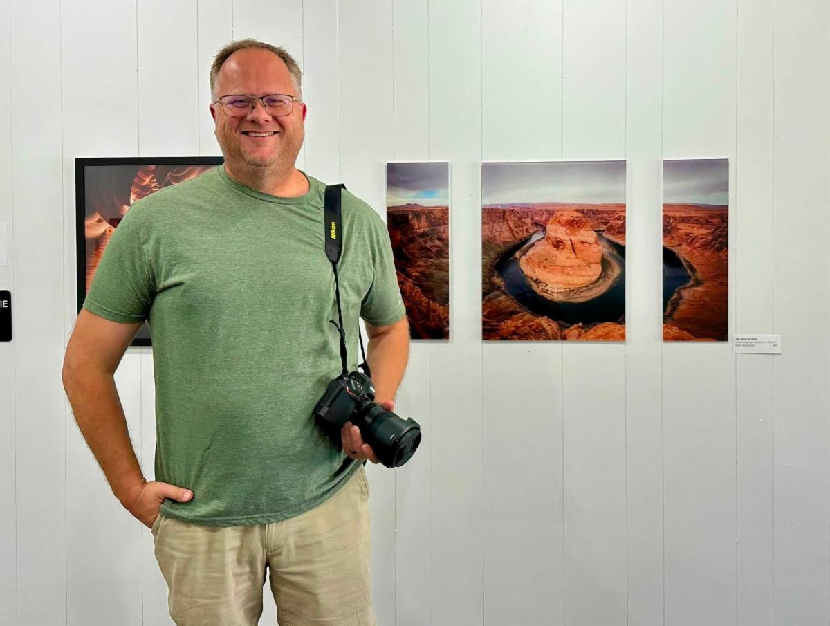 Brian Jeremiason poses in front of his hung photography at the SMAC Gallery
