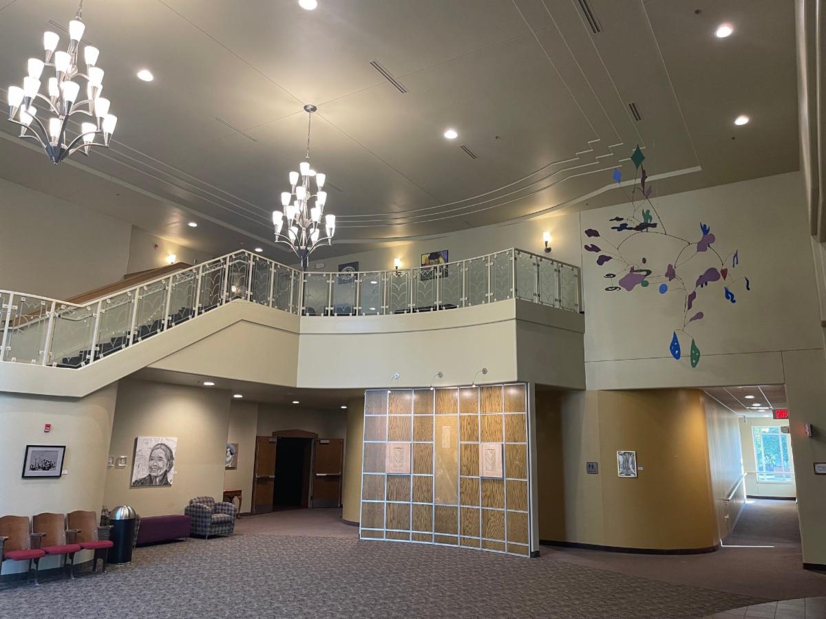 Interior lobby of the Worthington Memorial Auditorium. Set of stairs and chandeliers with art on walls and a an mobile from the ceiling.. 