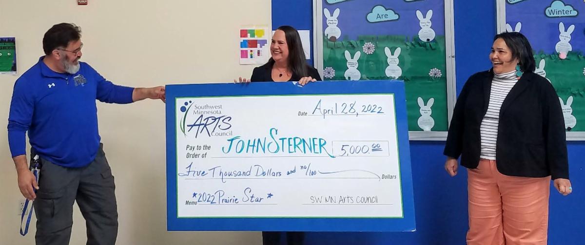 John Sterner accepting large check from Nicole DeBoer and Michele Sterner