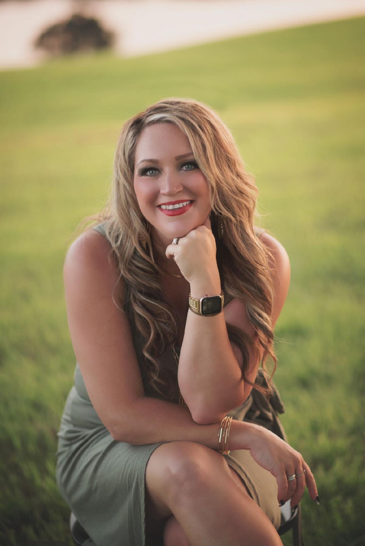Krista Hartman posing outside and smiling; background of green grass