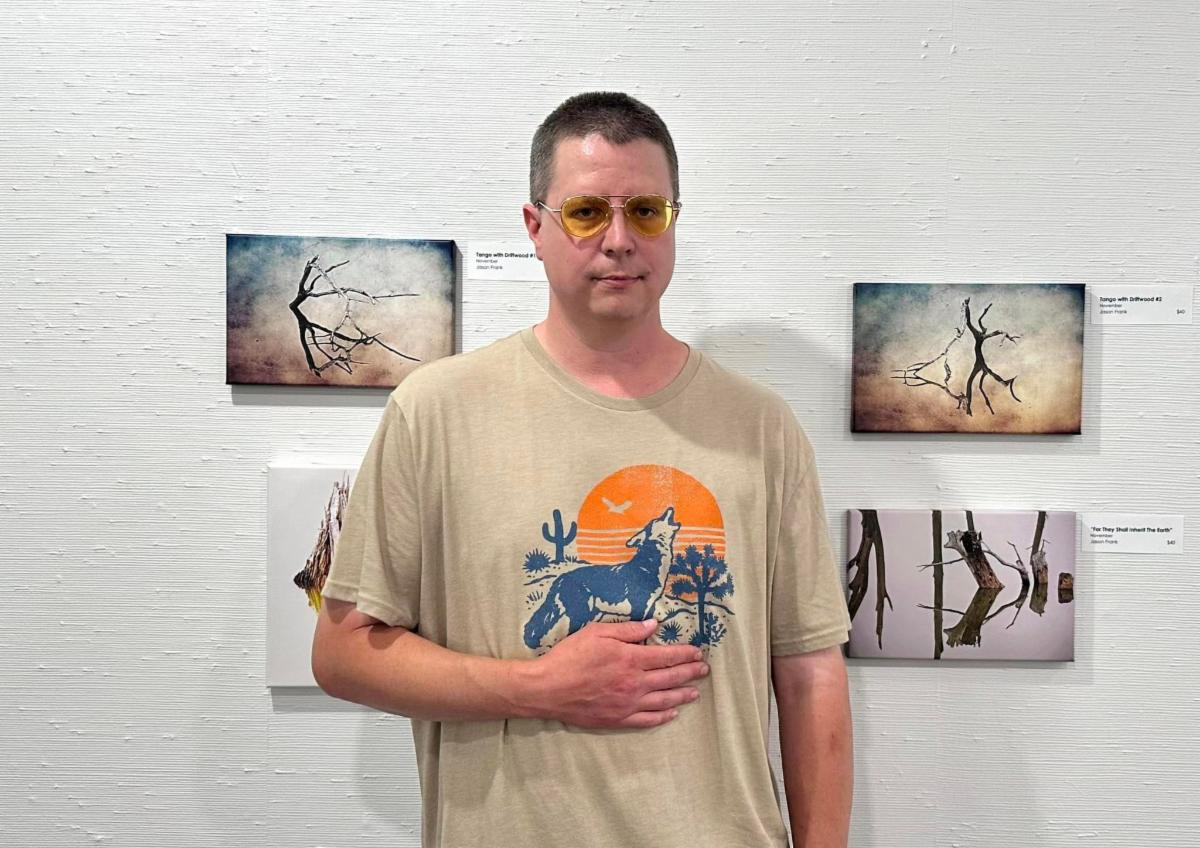 Jason Frank stands in front of his hanging photographs in the gallery