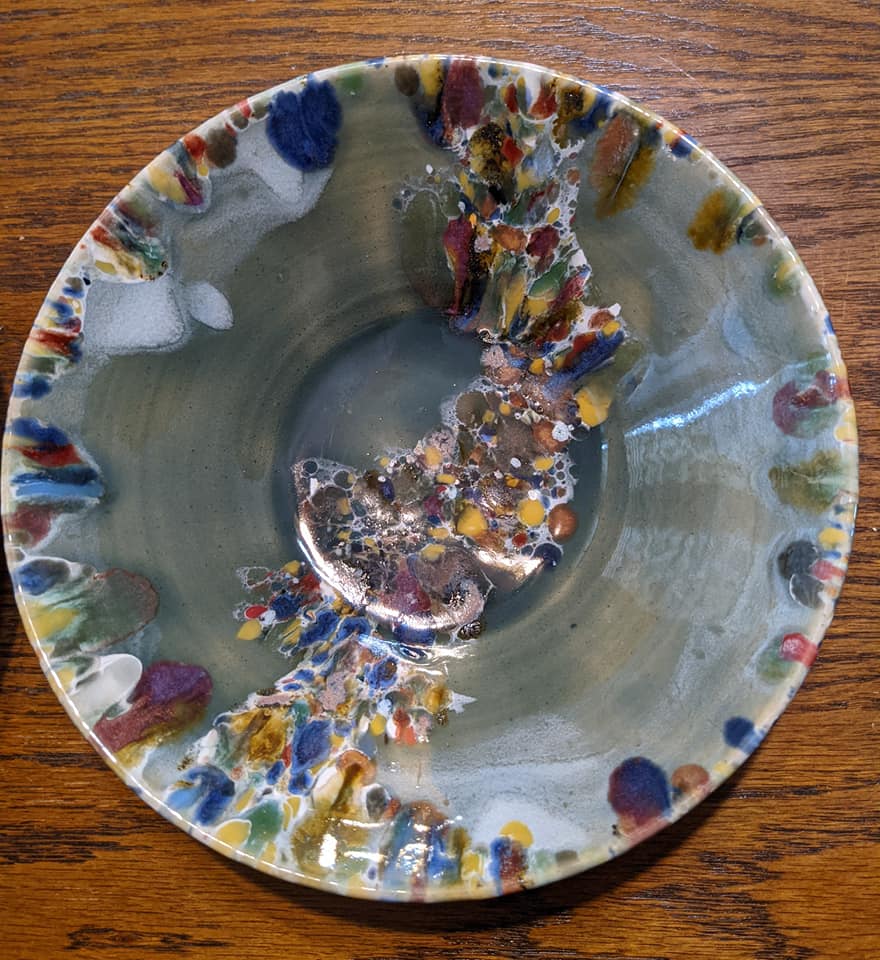 Ceramic bowl in mostly light green with specks of many colorful colors on the sides and a pattern through the middle