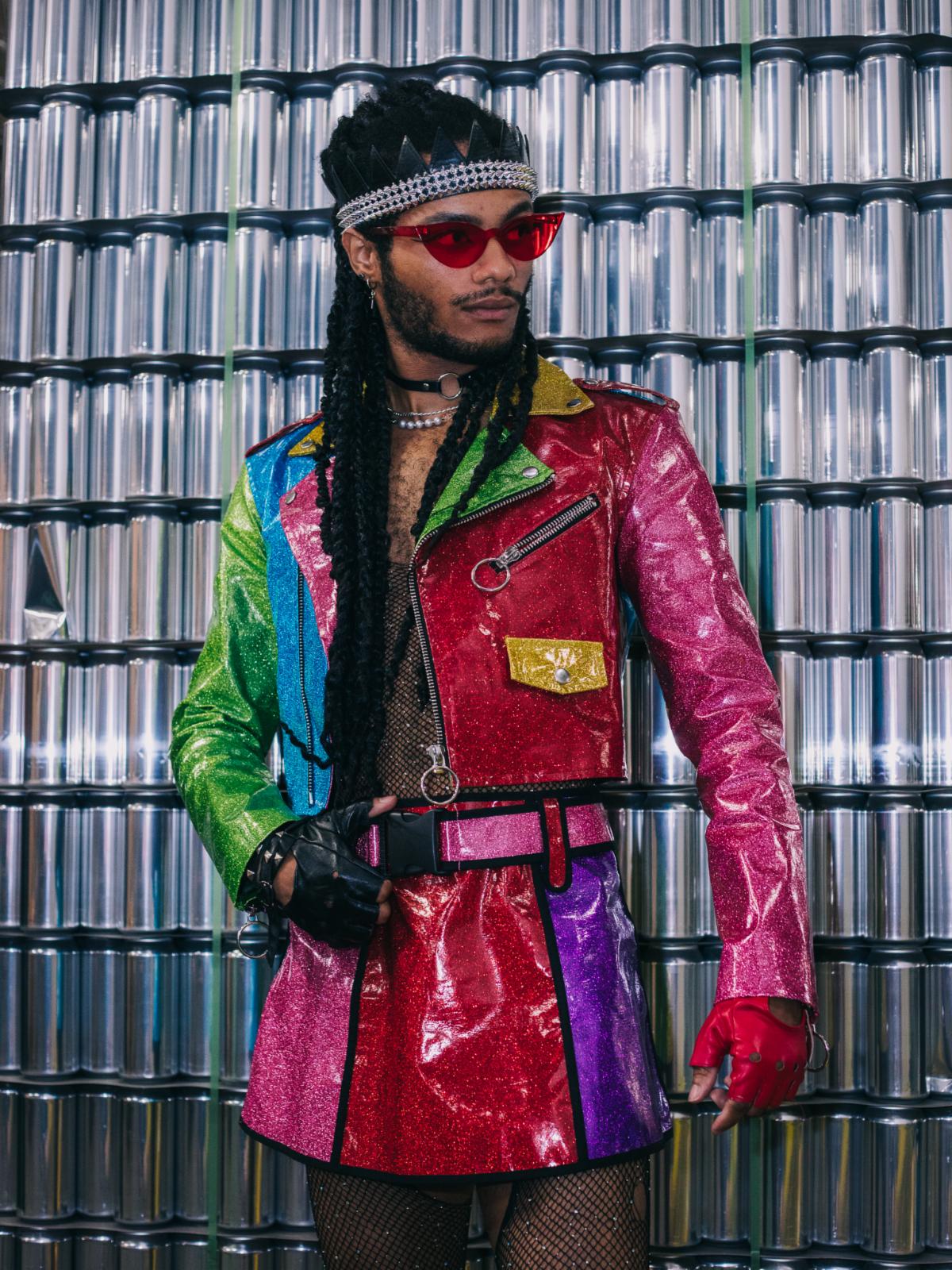 Drag performer in colorful clothes and sunglasses, light brown skin and black long dreadlocks