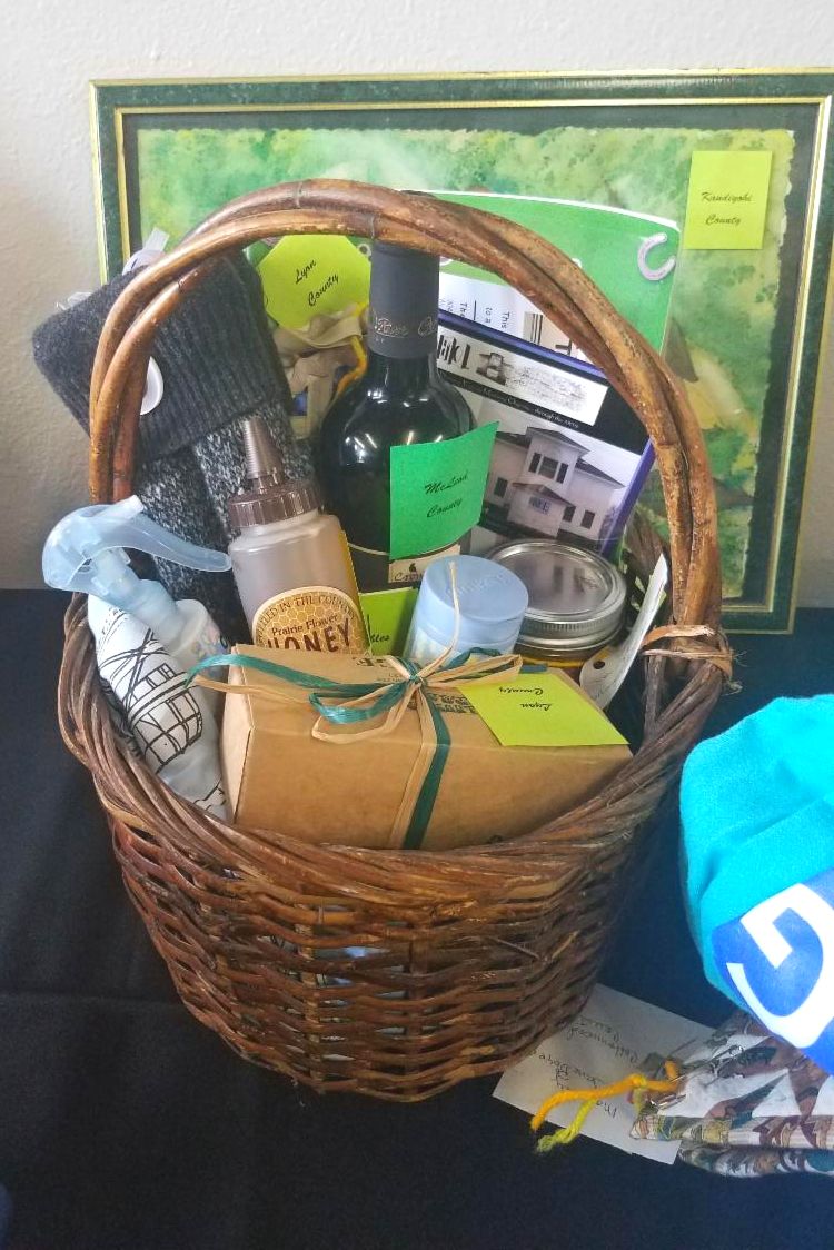 Goodie basket filled with honey, fudge, wine, gloves, and art