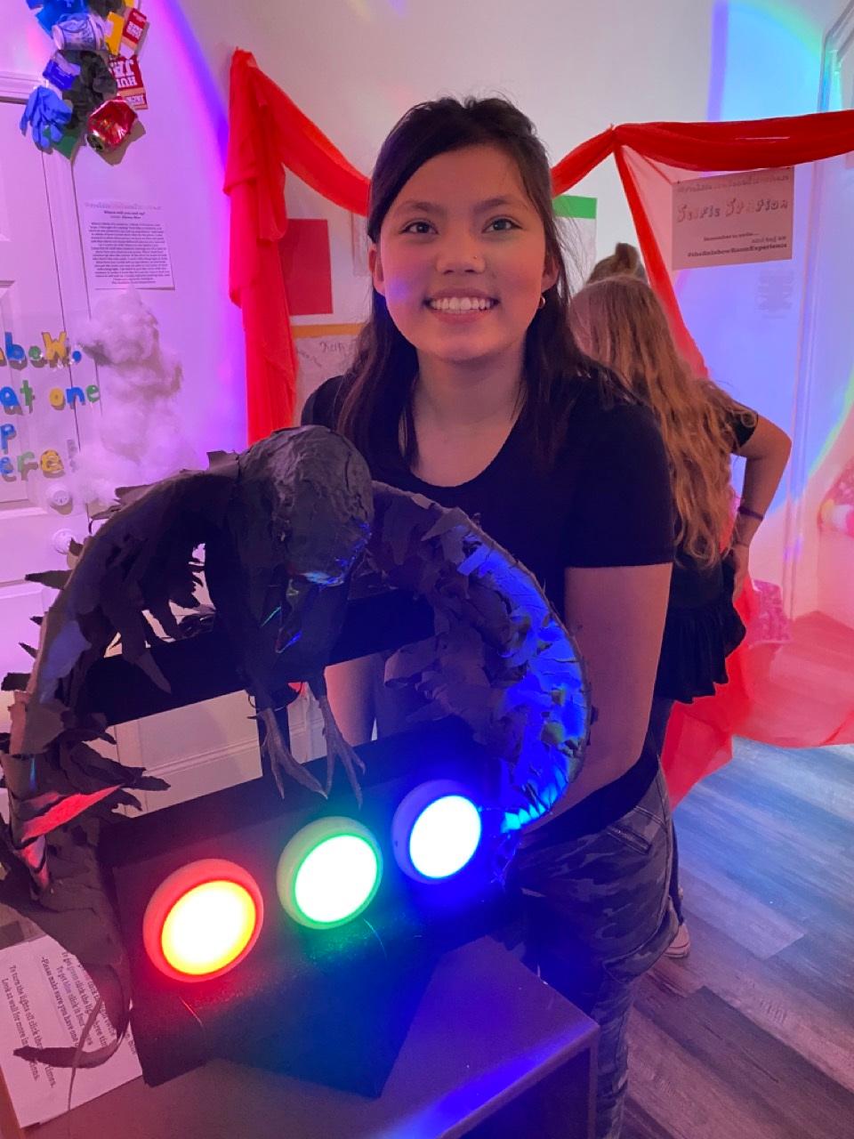 Young person standing by a rainbow light projector