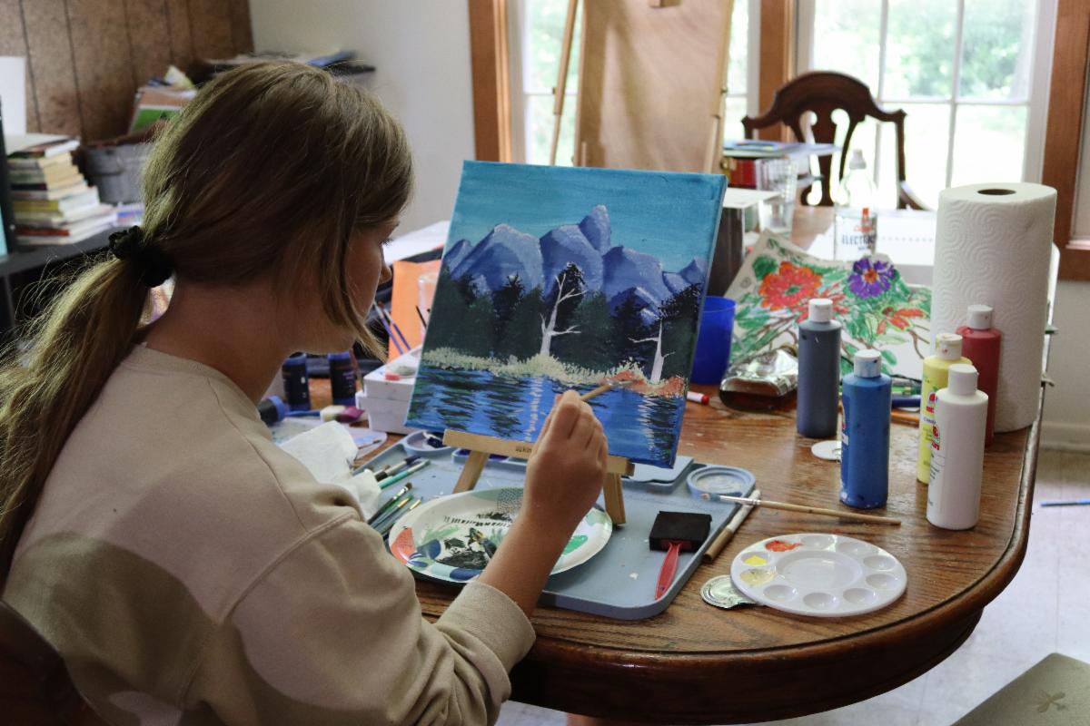 A young person painting a landscape on an easel