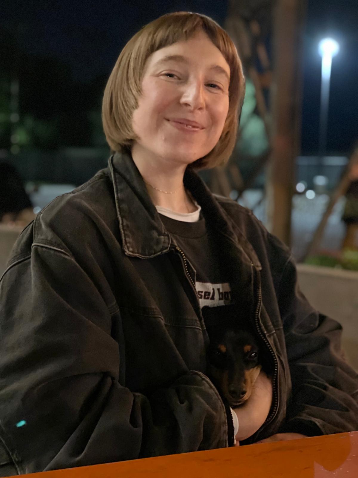 Simona Zappas holding puppy in her coat and smiling at the camera