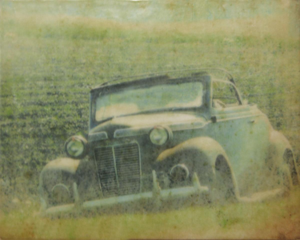 Mixed media piece of an old blue car in tall grass