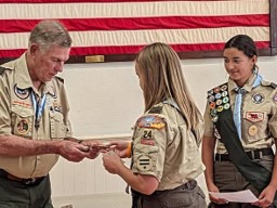 Scout leaders presenting an award or recognition to a young woman during a St. Helena Scout Troop Court of Honor ceremony.