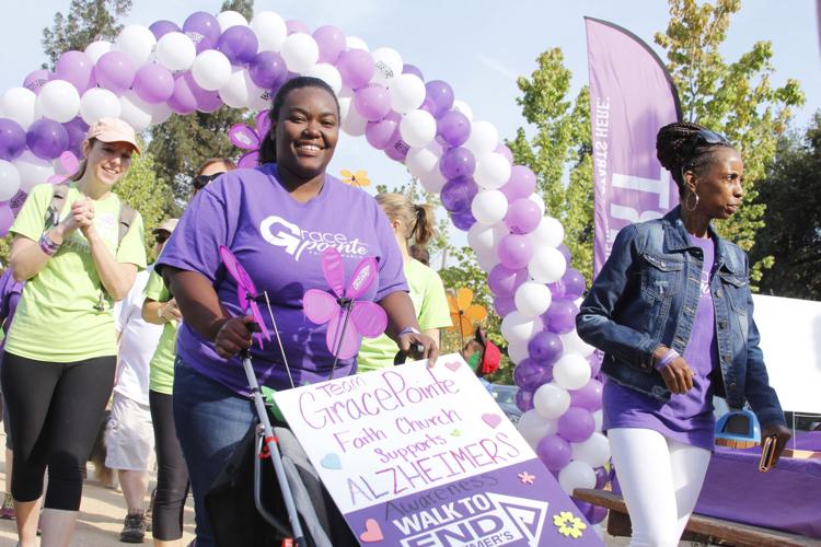 Participants walk together at the Napa Valley Walk to End Alzheimer’s beneath an arch of purple and white balloons. 