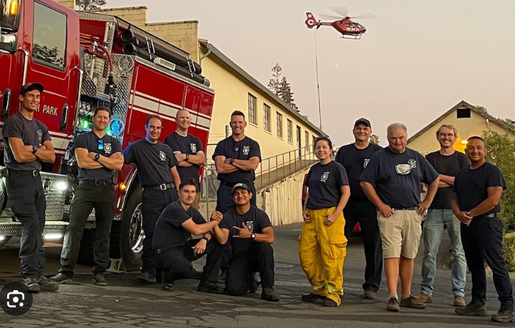 A group of men and women volunteer firefighters stand in front of a Napa County Fire engine.