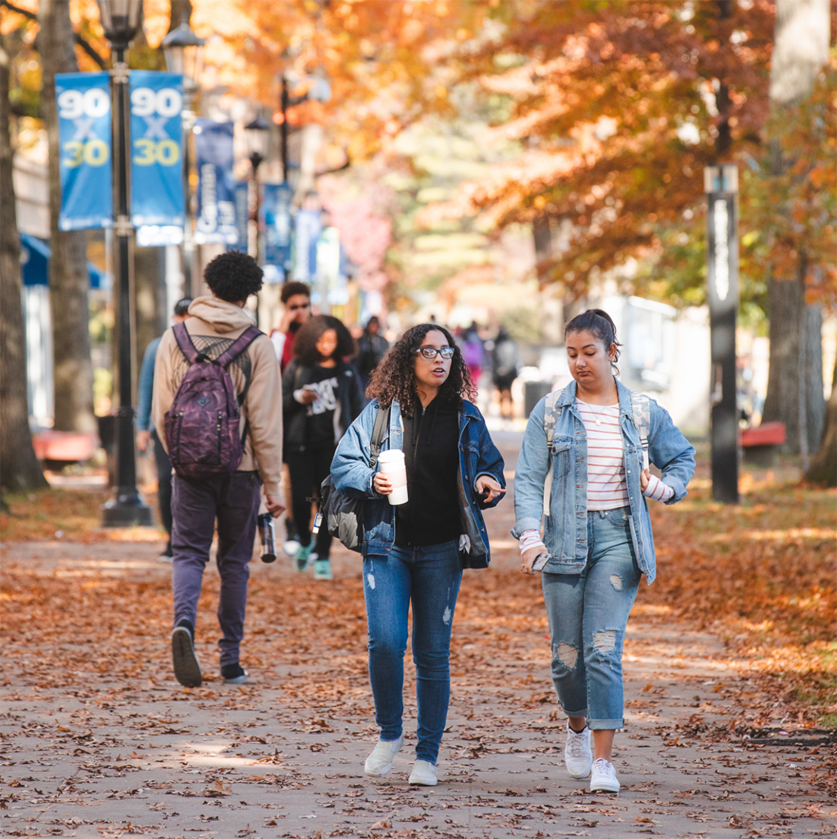 Photo of students walking on campus with Fall foliage in the background
