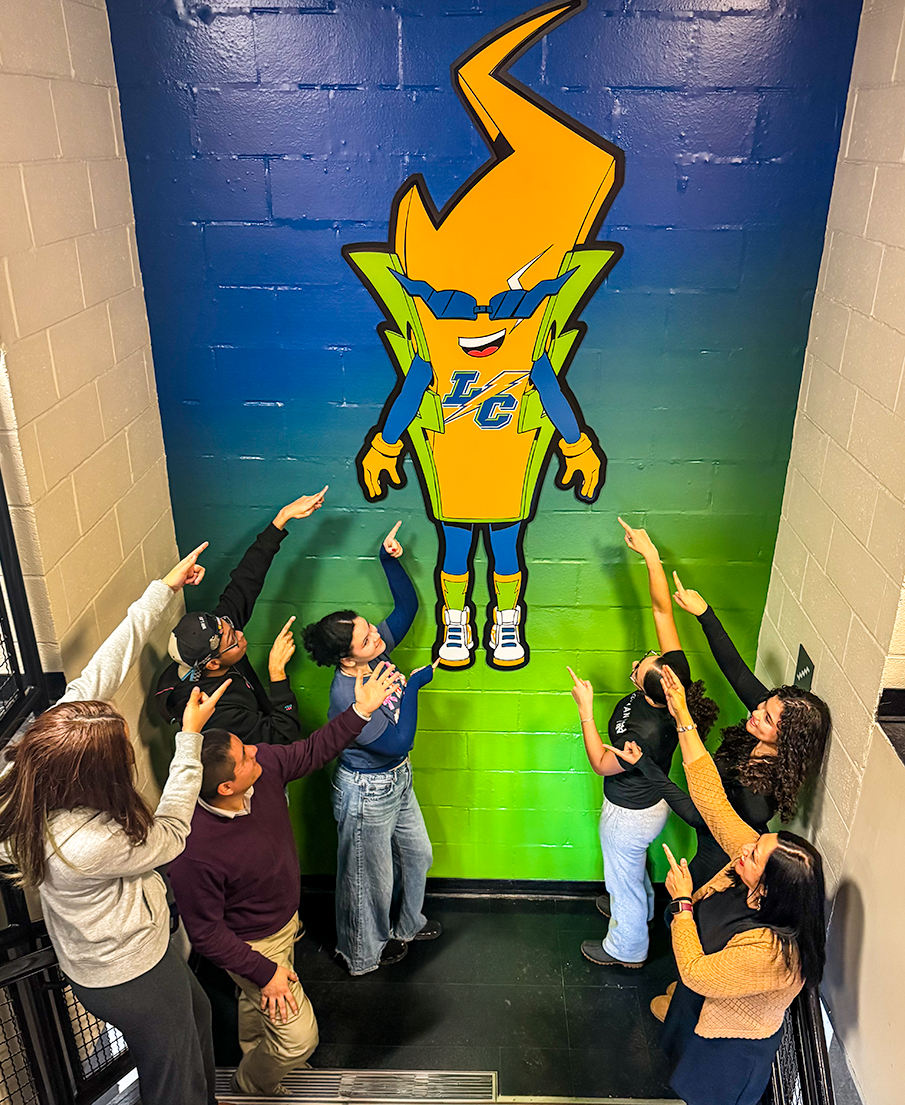 Students and staff point to smiling lightning bolt character